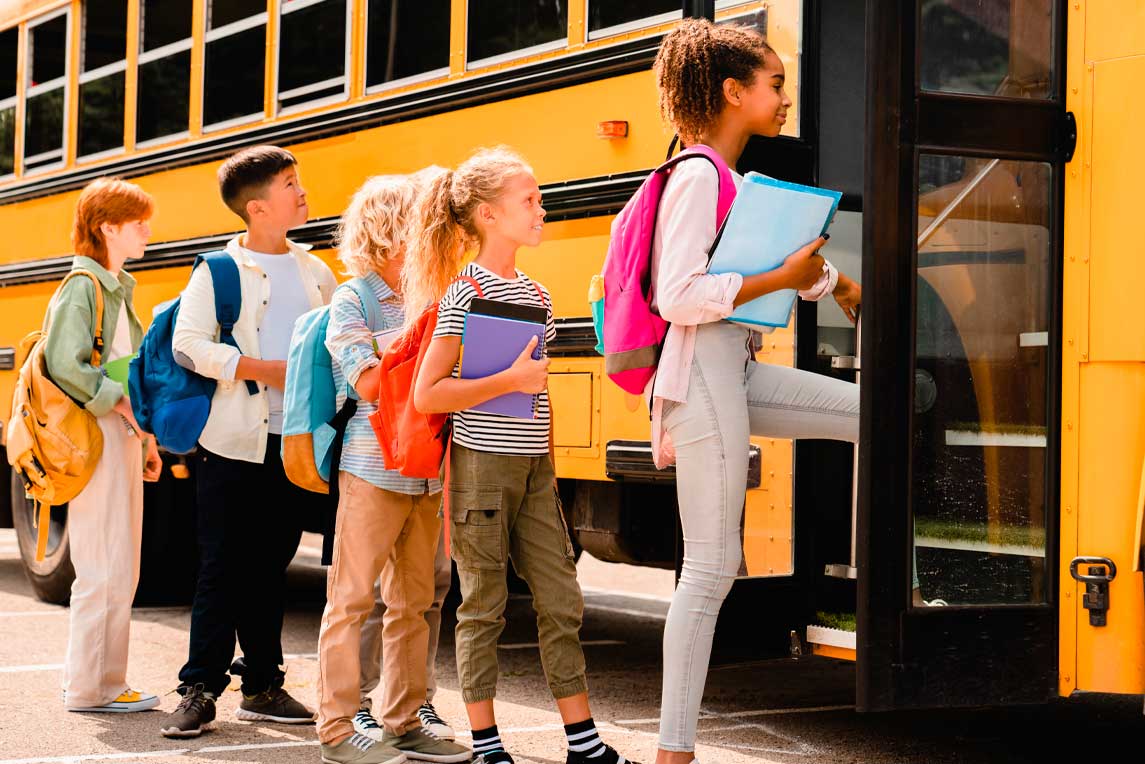 Schoolchildren kids pupils group of mixed-race classmates boarding school bus before going to lessons, coming back to school, standing in line. New educational year semester.
